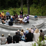 A drumming group performs on an outdoor stone patio for a small crowd