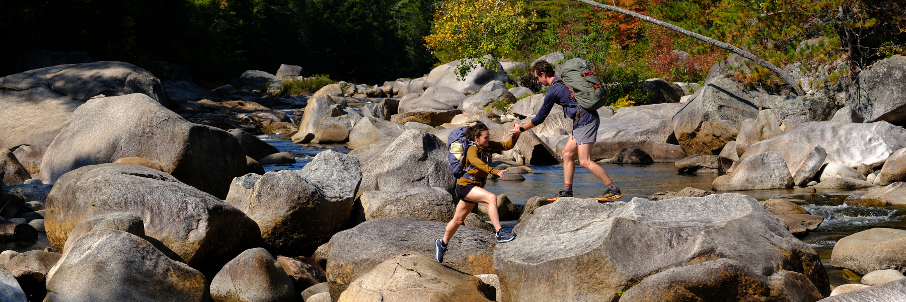 Two hikers ford a rocky river