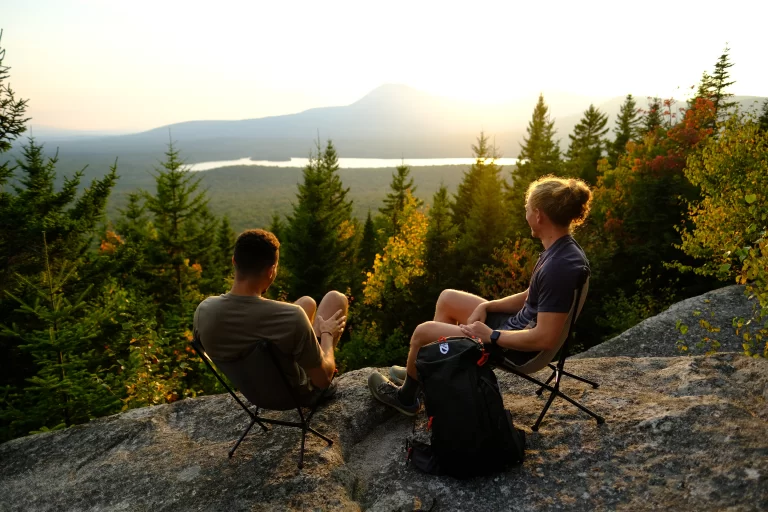 Two campers sitting atop Barnard Mountain viewing the sunset